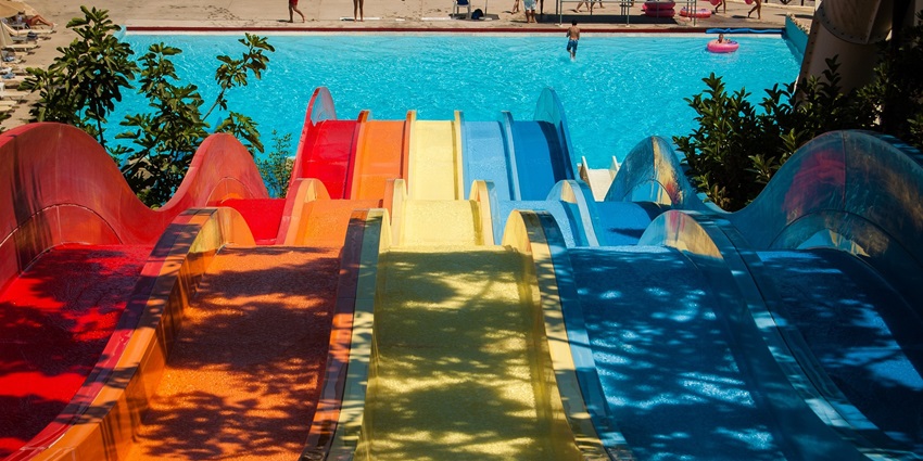 An image of different waterslides in colourful patterns with lush greenery nearby