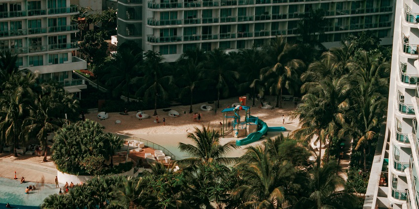 Green Hill Resort is a cityscape featuring tall modern buildings with green palm trees in the foreground.