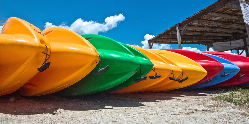 Brightly coloured kayaks stacked on a wooden dock with a shed for kayaking in Mumbai.