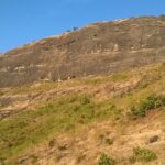 An image showing the Hasdar Fort of Maharashtra amidst the serene hills under clear blue sky.