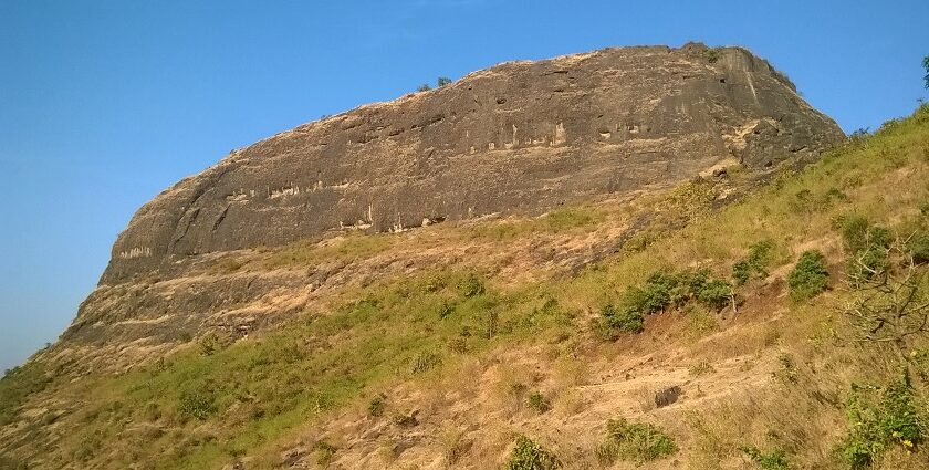 An image showing the Hasdar Fort of Maharashtra amidst the serene hills under clear blue sky.