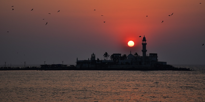 Sunset over the Arabian sea with the silhouette of Haji Ali Dargah mosque on an islet.