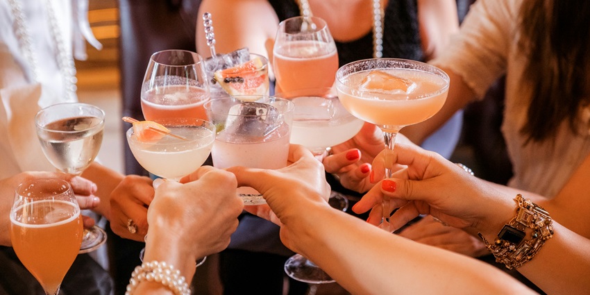 Image of a group of girls doing cheers with their colourful drinks in a restaurent