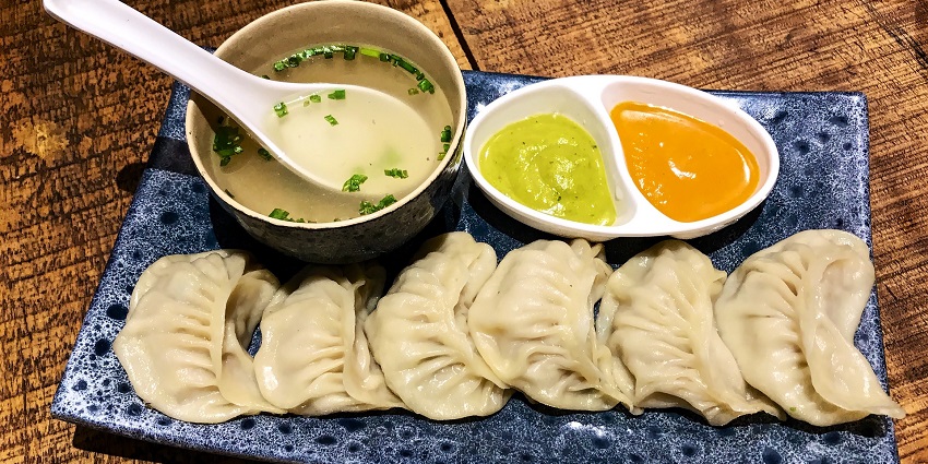 Northern Chinese dumplings with different sauces, garnished with herbs and oil.