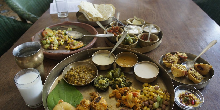 A Gujarati thali, including dal, vegetables, pickles, papad, beans, curd, and sweet.