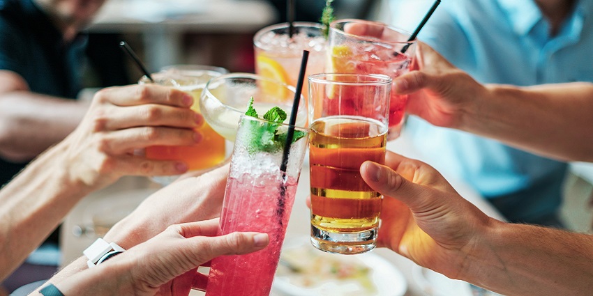 A group of people holding different kinds of drinks and cheering for a celebration.