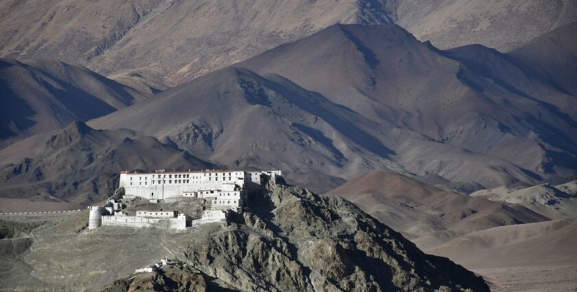 A view of a pristine white spiritual hub nestled in Ladakh surrounded by majestic peaks.