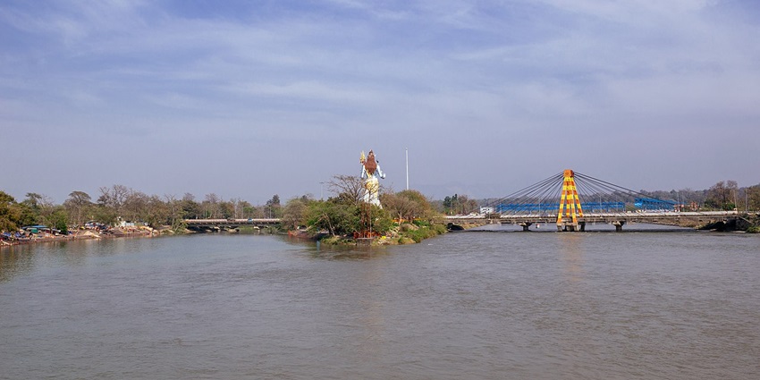 Statue of bhagwan shiv standing tall on the small river island in Ganga river