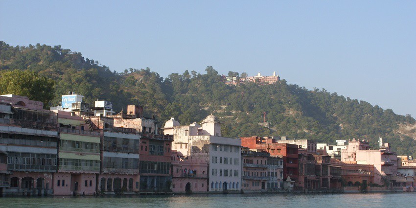 Houses lined up against the Ganga river flowing calmly.