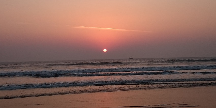 An image of a beach captured at a vibrant sunset, the hues reflecting in the water
