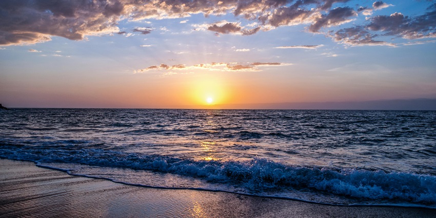 A view of the beach during sunset with golden hues, a tourist attraction in the region.