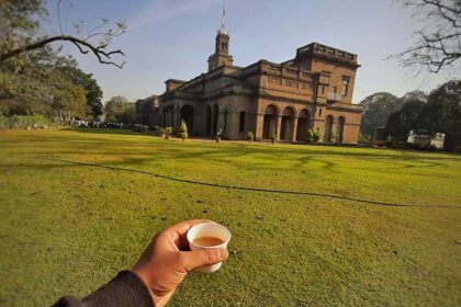 A picture showing a cup of tea along with the iconic Savitribai Phule University in Pune.