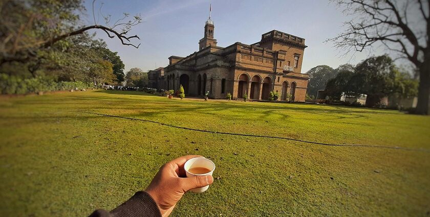 A picture showing a cup of tea along with the iconic Savitribai Phule University in Pune.