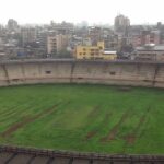 A picture showing a cricket stadium in Thane with tall buildings visible in the background.