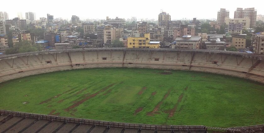 A picture showing a cricket stadium in Thane with tall buildings visible in the background.