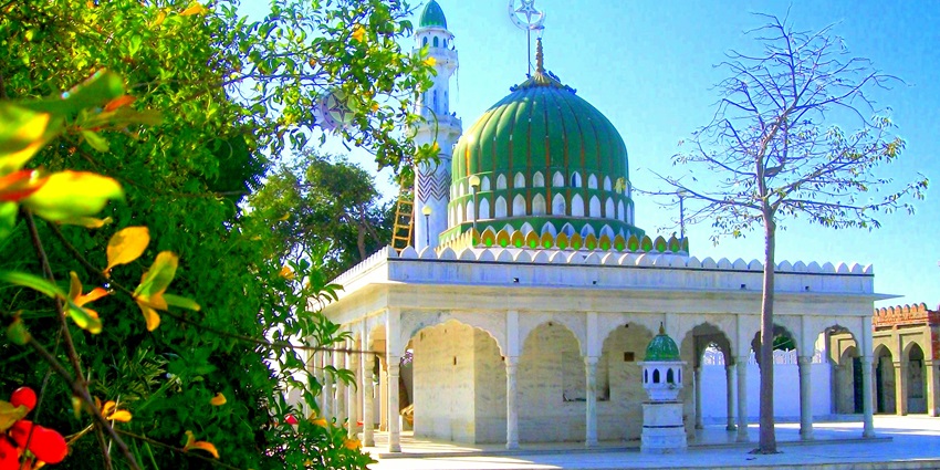 View of the Hazrat Baba Tajjuddin Dargah surrounded by lush trees on a sunny day
