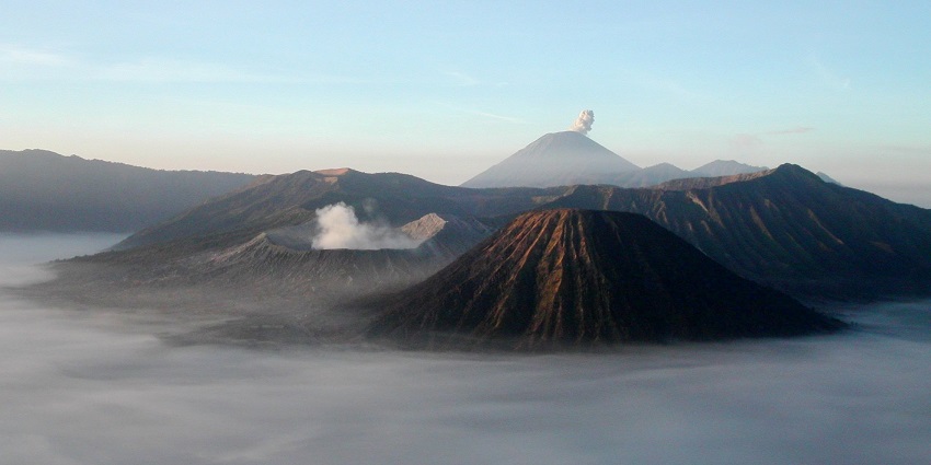 The sunrise view at Mount Bromo shows its active volcano smoke and Mount Semeru.