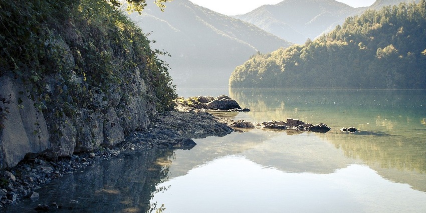 Calm lake surrounded by rocks and autumn trees, reflecting the serene natural beauty.