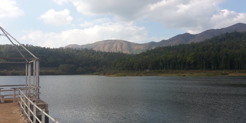 Scenic view of Hirekolale Lake surrounded by hills and lush greenery