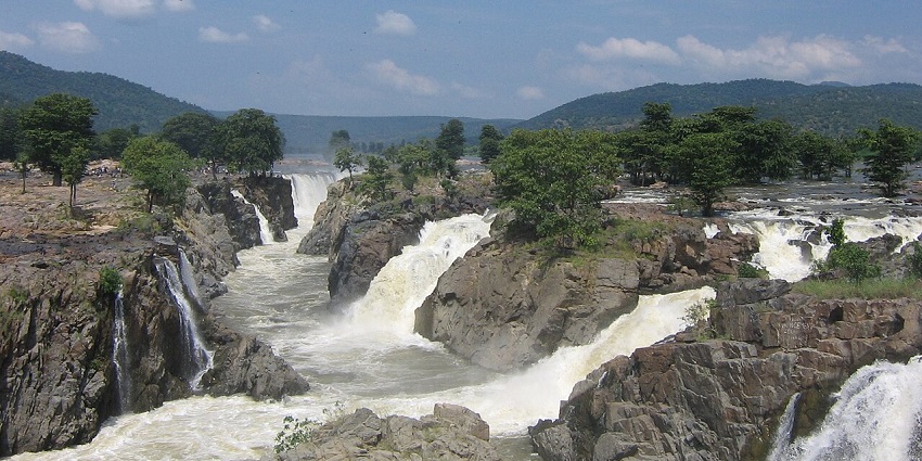 A scenic view of water cascading through rocky terrains at the Hogenakkal Falls.