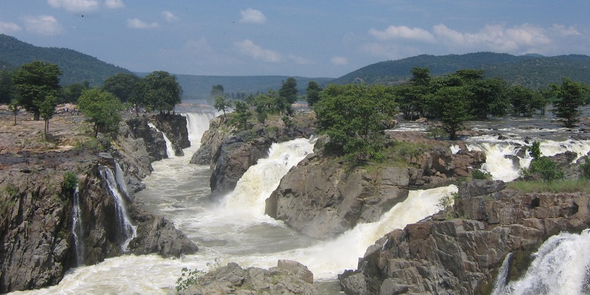 Hogenakkal Waterfalls cascading down rocky cliffs, surrounded by lush greenery.