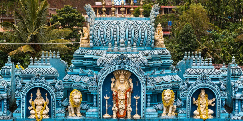 Intricate temple carvings with deities and lions, surrounded by lush greenery