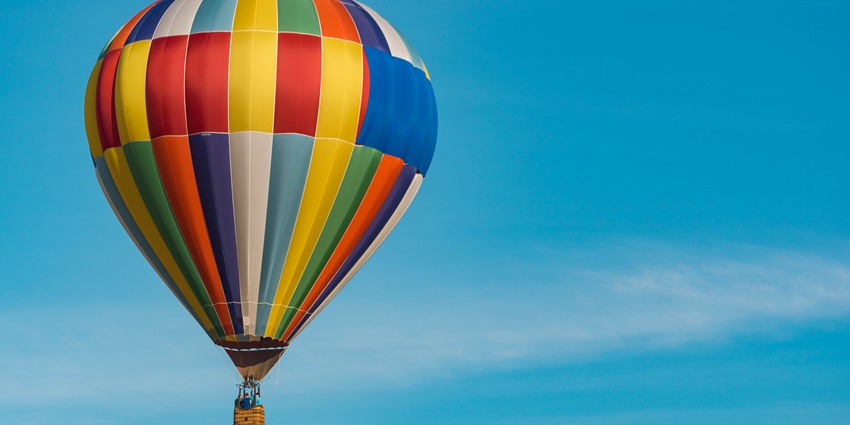 A view of a colourful hot air balloon gliding high up in the air in Assolda Village.