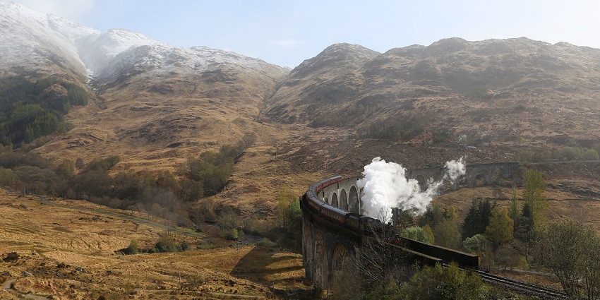 Train arriving at a bustling railroad station with travellers and vibrant surroundings.