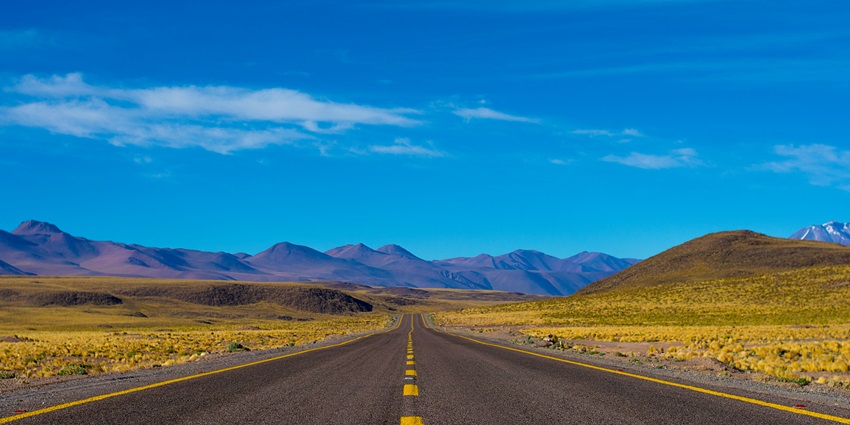 A view of a road in India, showing scenic views of the surroundings and a clear blue sky.