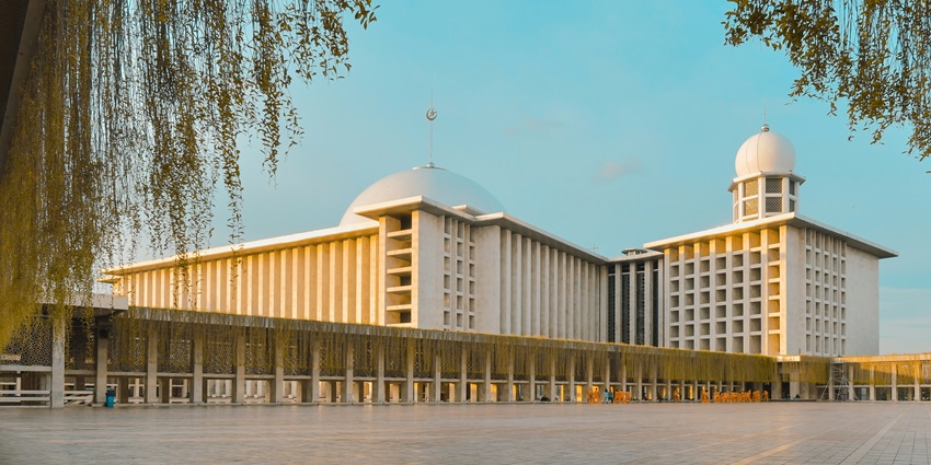 An image of Istiqlal Mosque in Jakarta, a large white structure with two prominent domes.