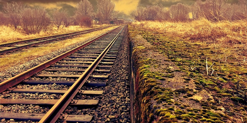 Railway tracks stretching ahead with a train in the distance, symbolising travel and transit.