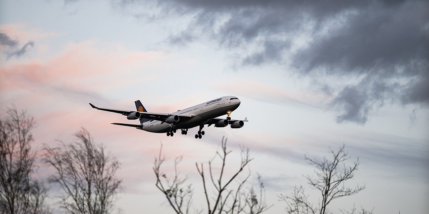 Airplane flying high in the sky, showcasing its wings against a blue backdrop