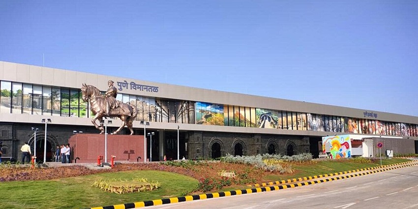 Wide view of the departure lounge at Pune Airport, featuring seating and large windows.