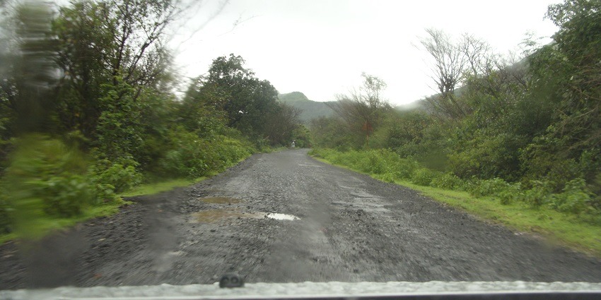 A car drives through the scenic Western Ghats on the way to Manimuthar Waterfalls.