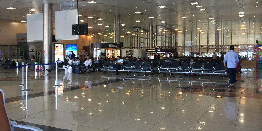 Wide view of the departure lounge at Pune Airport, featuring seating and large windows.