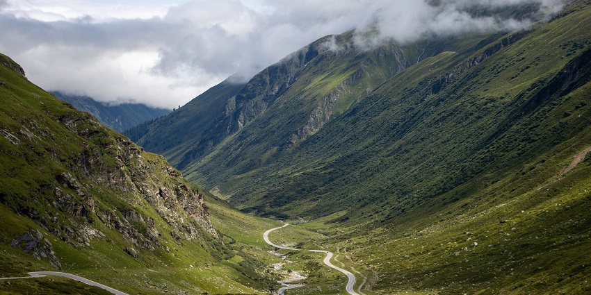 A mesmerising view of a winding road passing through a lush green mountain range.