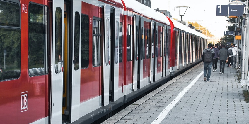 A train arrives at a quiet railway platform, with tracks stretching into the distance