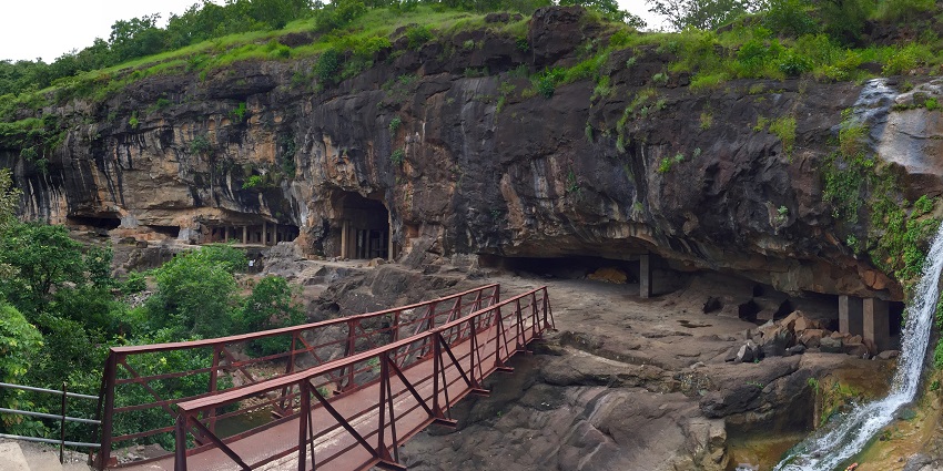 Airport terminal building with a curved roof and parked vehicles,To reach Pitalkhora Caves.