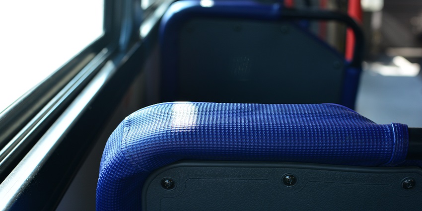A sleek bus parked against a vibrant city backdrop, ready for passengers to board.