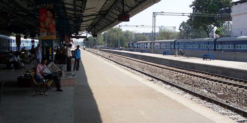 Historic railway station with arched facades and clock tower under a bright, clear sky