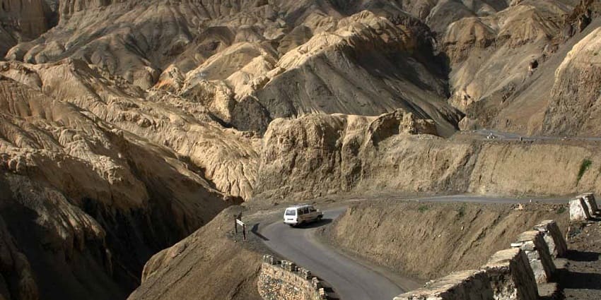 A picture of a highway in Ladakh with views of majestic mountains in the background