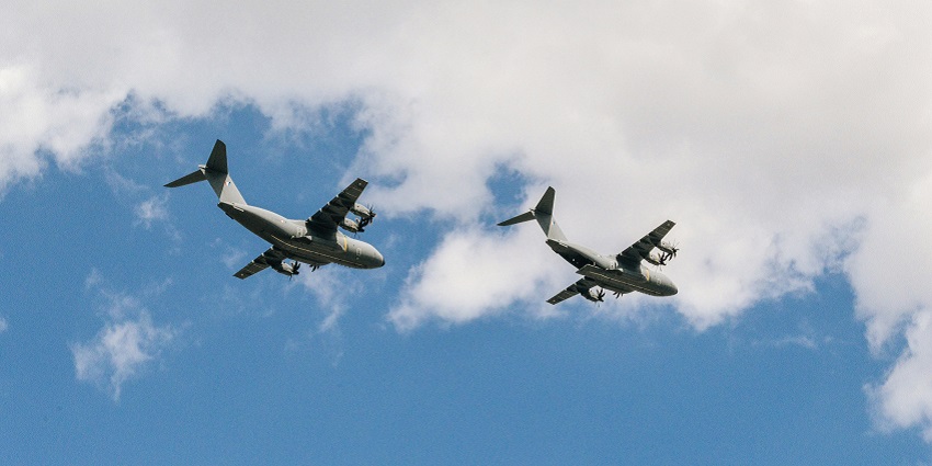 A stunning view of two white and grey aeroplanes in the clear blue skies during the day.