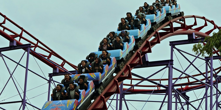 A vibrant roller coaster twists through an amusement park, thrilling riders above colourful attractions.