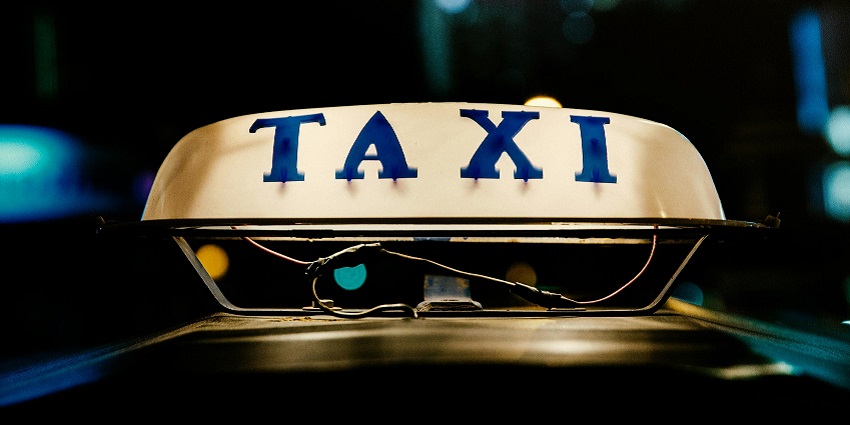 A mesmerising view of a taxi with a sign board with neon lights during the nighttime.