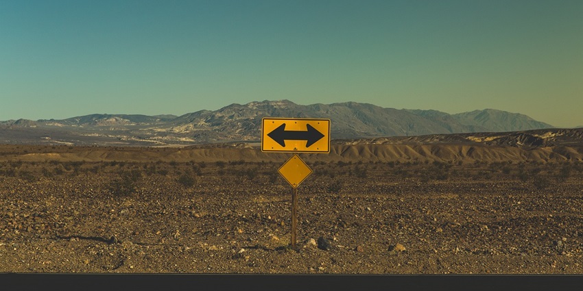 Barren landscape with weathered arrows pointing in different directions on the ground.