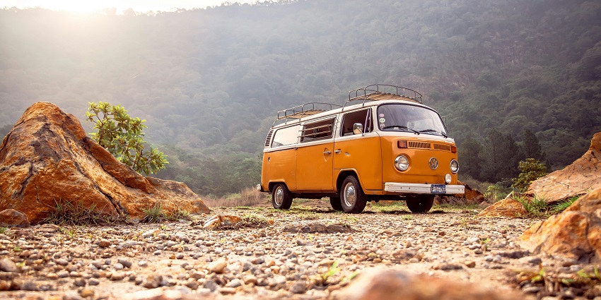 Image of a low angle photo of volkswagen kombi around the mountains during day time