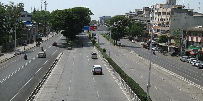 A view of the Old Pune-Mumbai Highway with vehicles on the road, surrounded by greenery.