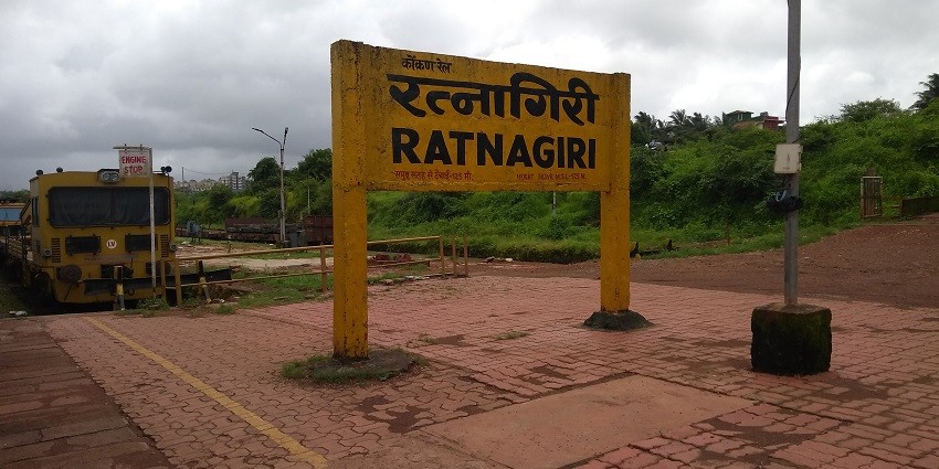 Ratnagiri railway station platform with signboard and greenery in the background.