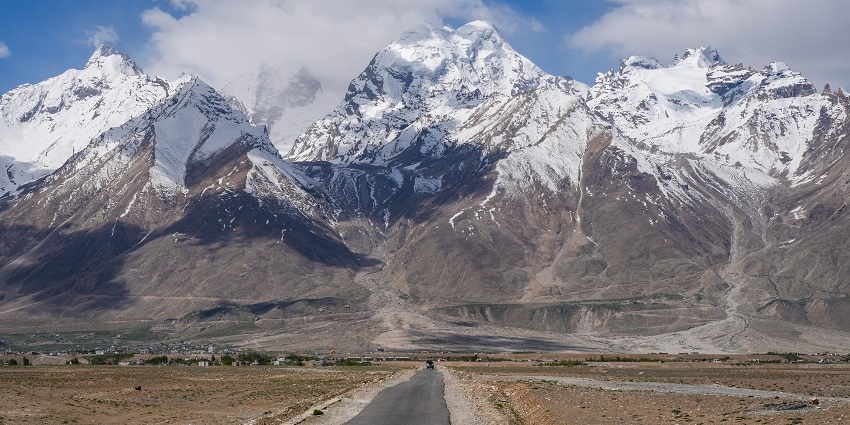 A breathtaking view of a winding road with snow-covered mountains in the background.