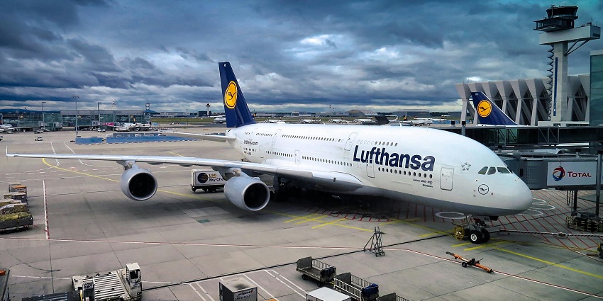 A white and blue Lufthansa aeroplane on a runway, preparing for takeoff in Maharashtra.